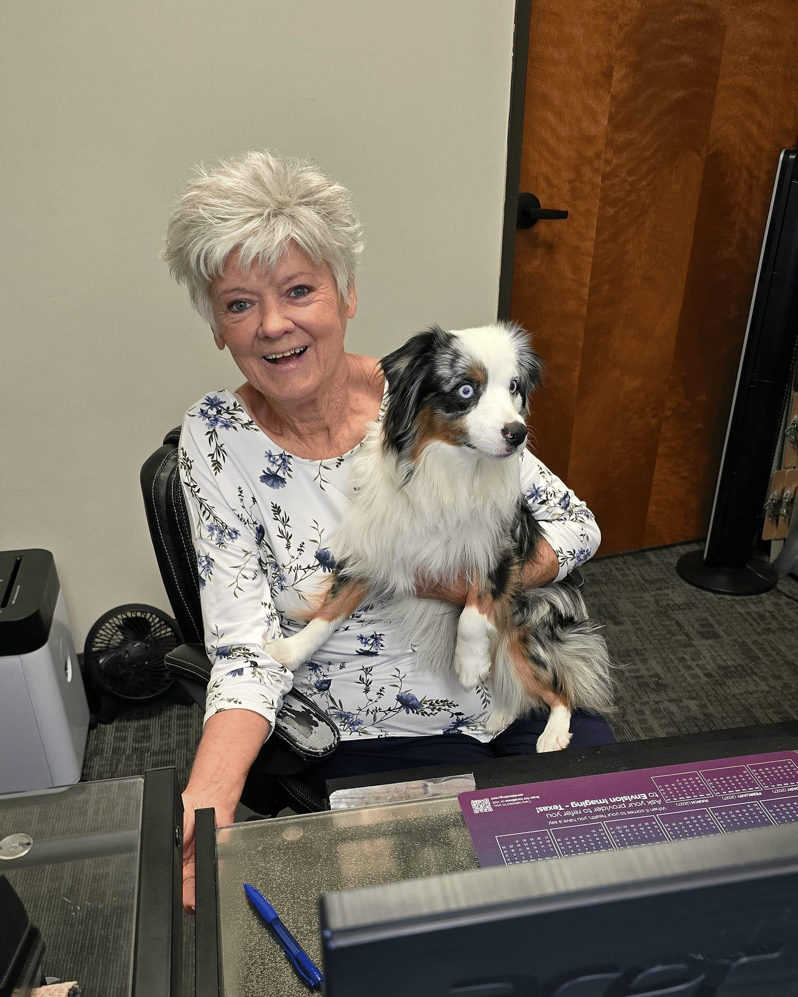 Debbie holds the office dog behind the front desk at Mansfield Spinal Care in Mansfield, Texas.